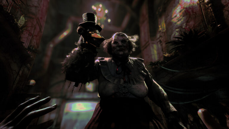 Kadr z gry The Outlast Trials. Mroczny, stylizowany obraz przedstawiający postać w klaunskim makijażu i stroju, trzymającego marionetkę, stojącego naprzeciwko perspektywy pierwszej osoby, z rozmytymi światełkami w tle.