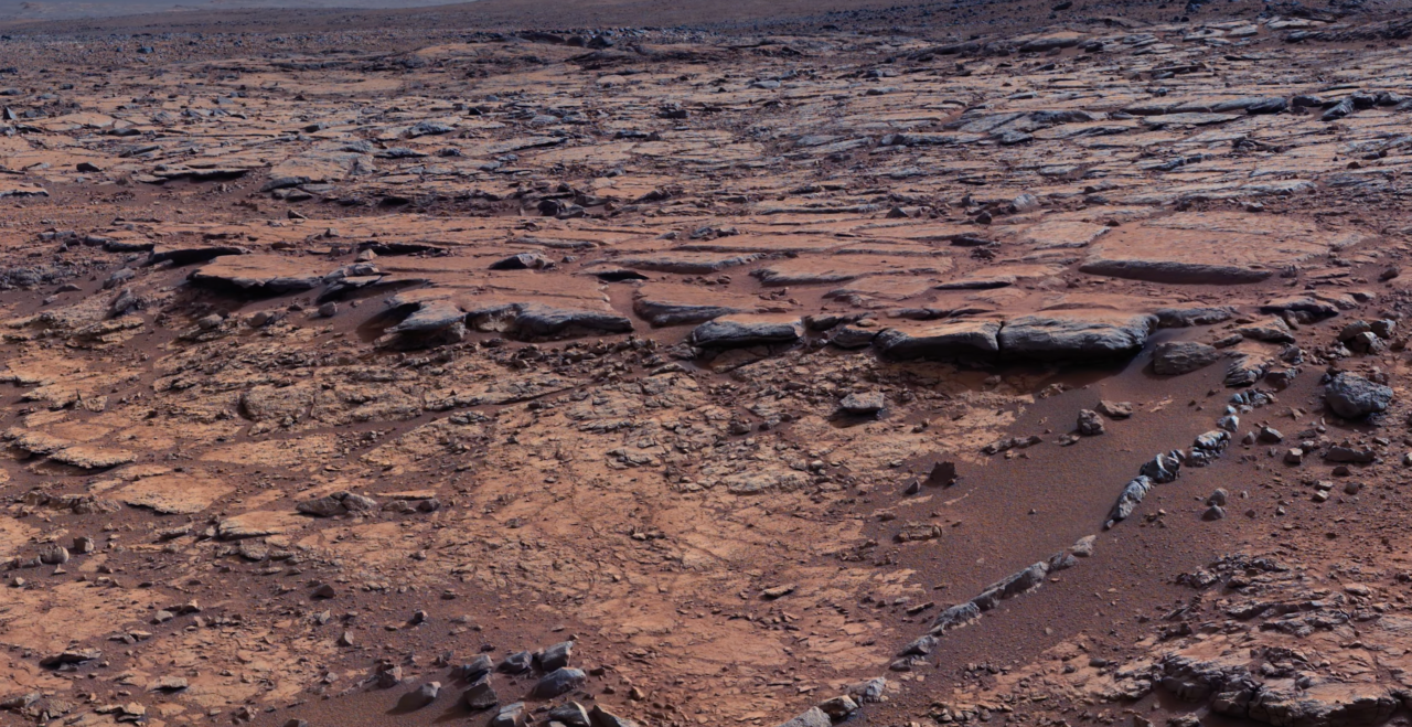 Kamienna i piaszczysta powierzchnia Marsa z licznymi skałami i żwirami.