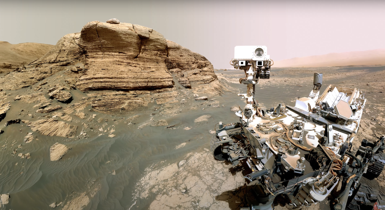 Łazik marsjański Curiosity wykonujący selfie na tle skał marsjańskiego krajobrazu.