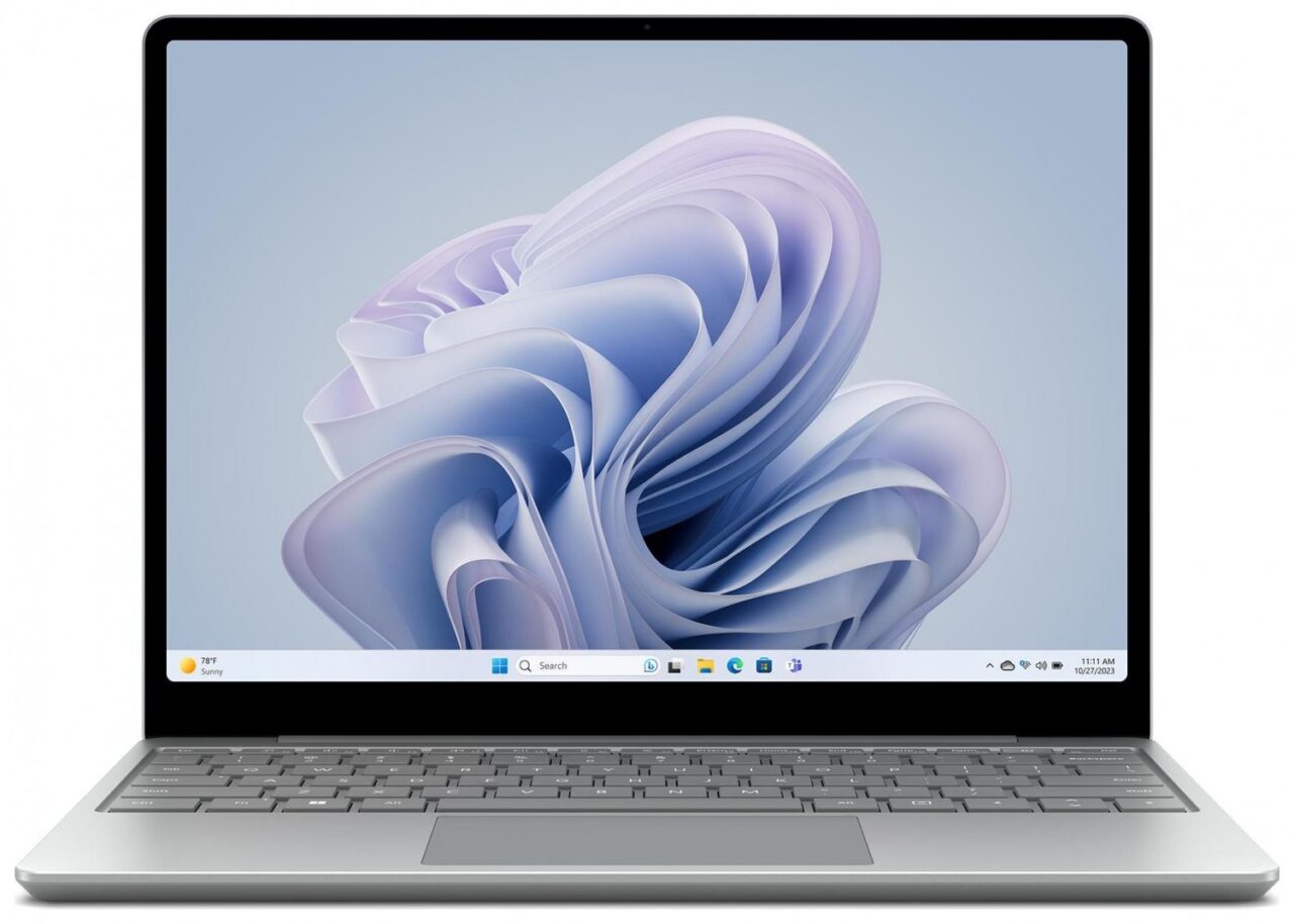 Laptop z otwartym pokrywą i widocznym ekranem wyświetlającym abstrakcyjne, falujące formy w odcieniach błękitu na tle pulpitu z paskiem zadań i ikonami.