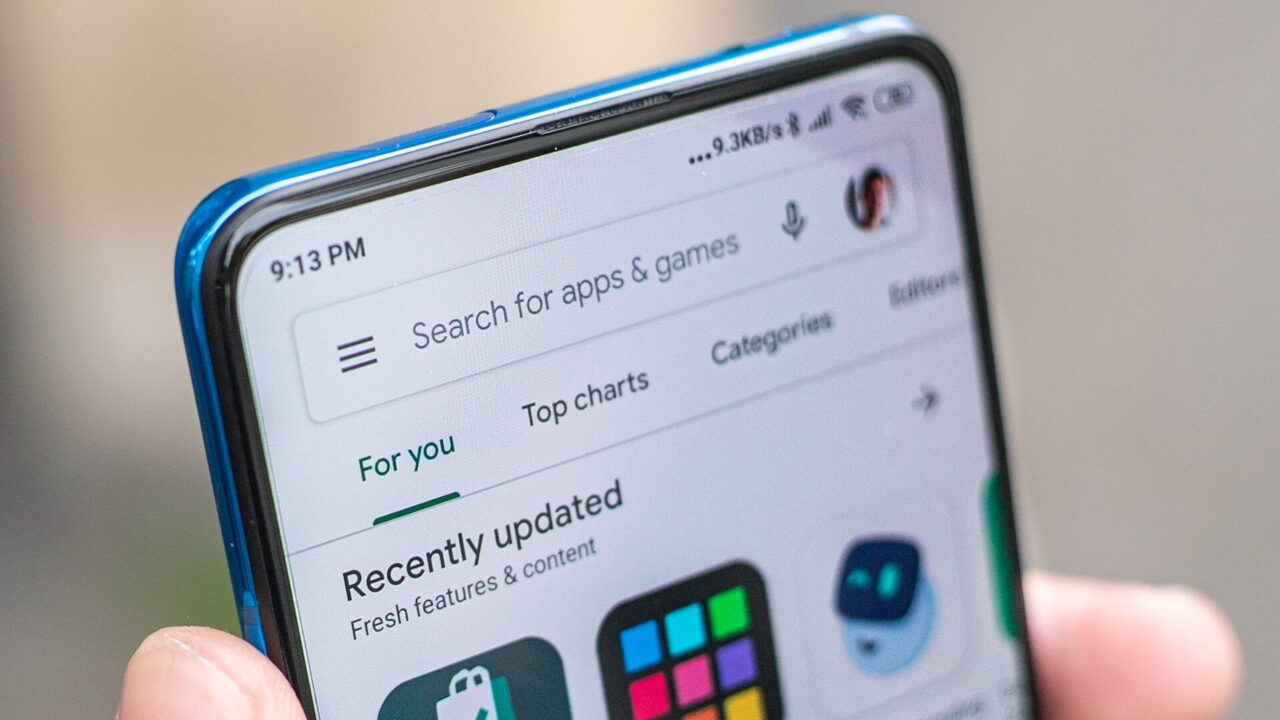 Ekran smartfona wyświetlający sklep z aplikacjami z widoczną wyszukiwarką i kartami "Dla Ciebie", "Top charts" oraz "Kategorie". W sklepie mogą być aplikacje które stanowią zagrożenie dla smartfonów z androidem