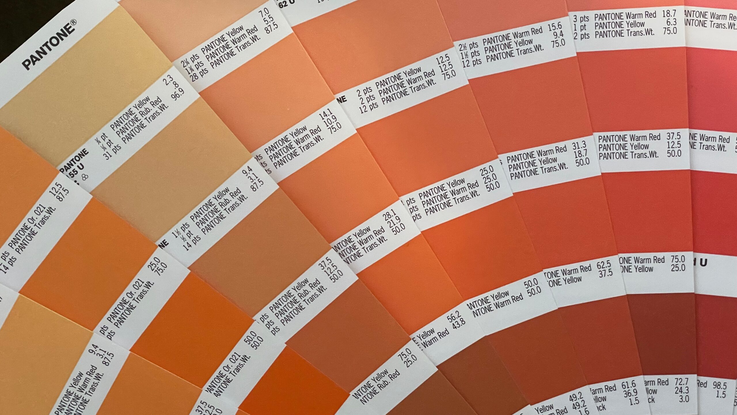 Paleta kolorów Pantone z próbkami odcieni pomarańczowych i czerwonych, każda z oznaczeniem i proporcjami mieszania barw.
