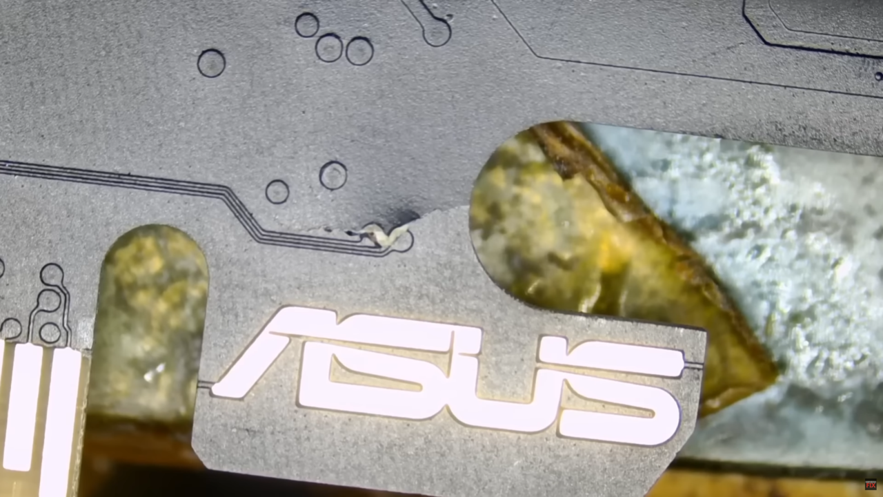 Zbliżenie na srebrną metalową płytę z wyciętym logo "ASUS", przez które prześwituje rozmazane tło.