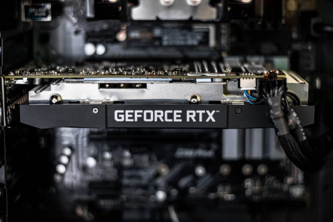 Karta graficzna GeForce RTX zamontowana w obudowie komputera, z widocznymi złączami i okablowaniem w tle.