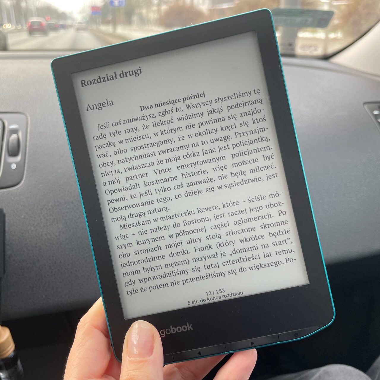 Czytanie książki elektronicznej na czytniku e-book w samochodzie, wyświetlany jest tekst w języku polskim na ekranie.