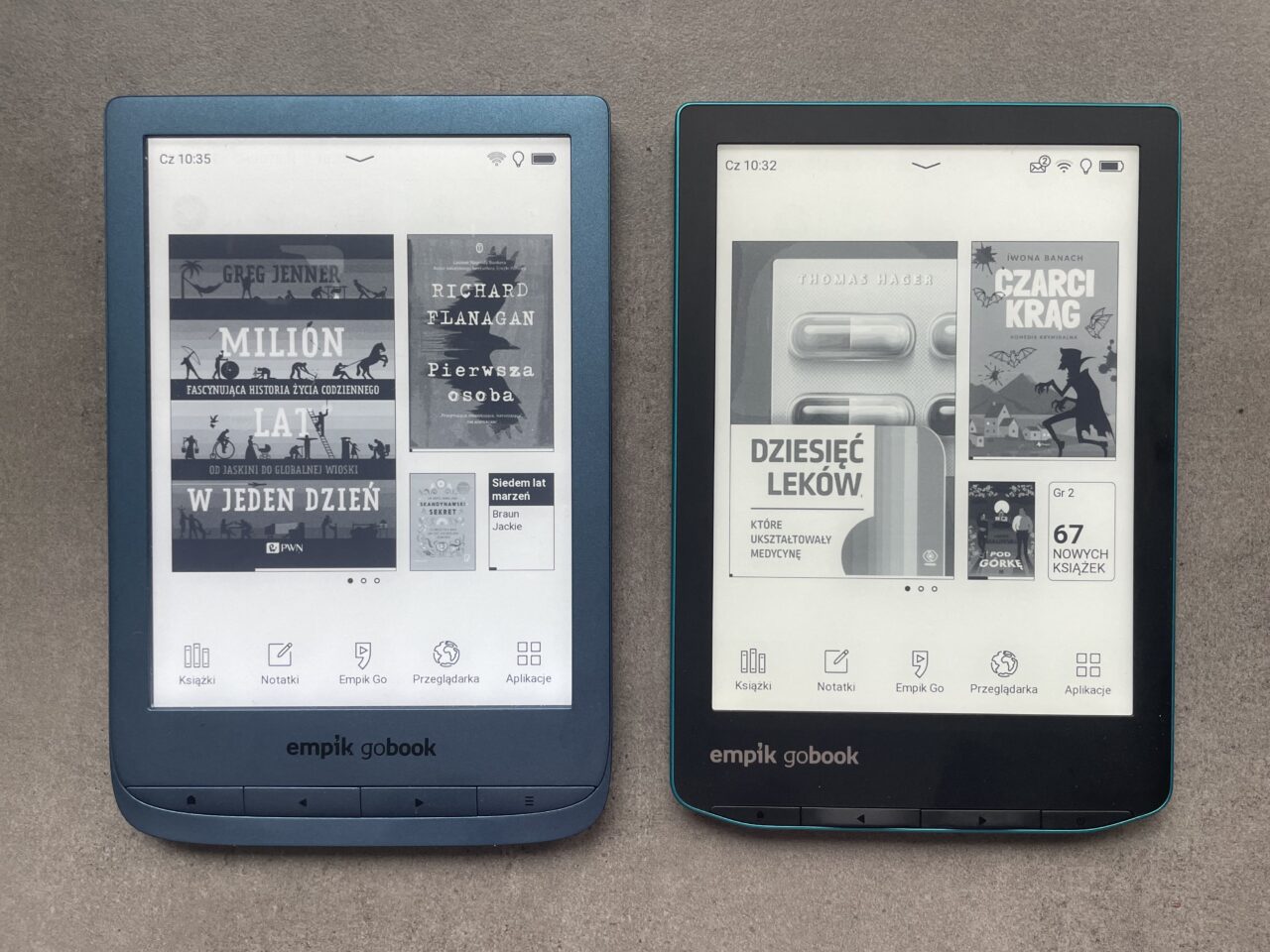 Dwa czytniki e-booków marki Empik GoBook na szarym tle. Lewy czytnik z niebieską obudową wyświetla ekran główny z okładkami książek, w tym "Million lat w jeden dzień" i "Pierwsza osoba". Prawy czytnik z zielonkawą obudową pokazuje ekran z okładką książki "Dziesięć leków, które ukształtowały medycynę" i promocją "67 nowych książek". Na obu ekranach widoczne są godziny i ikony aplikacji.