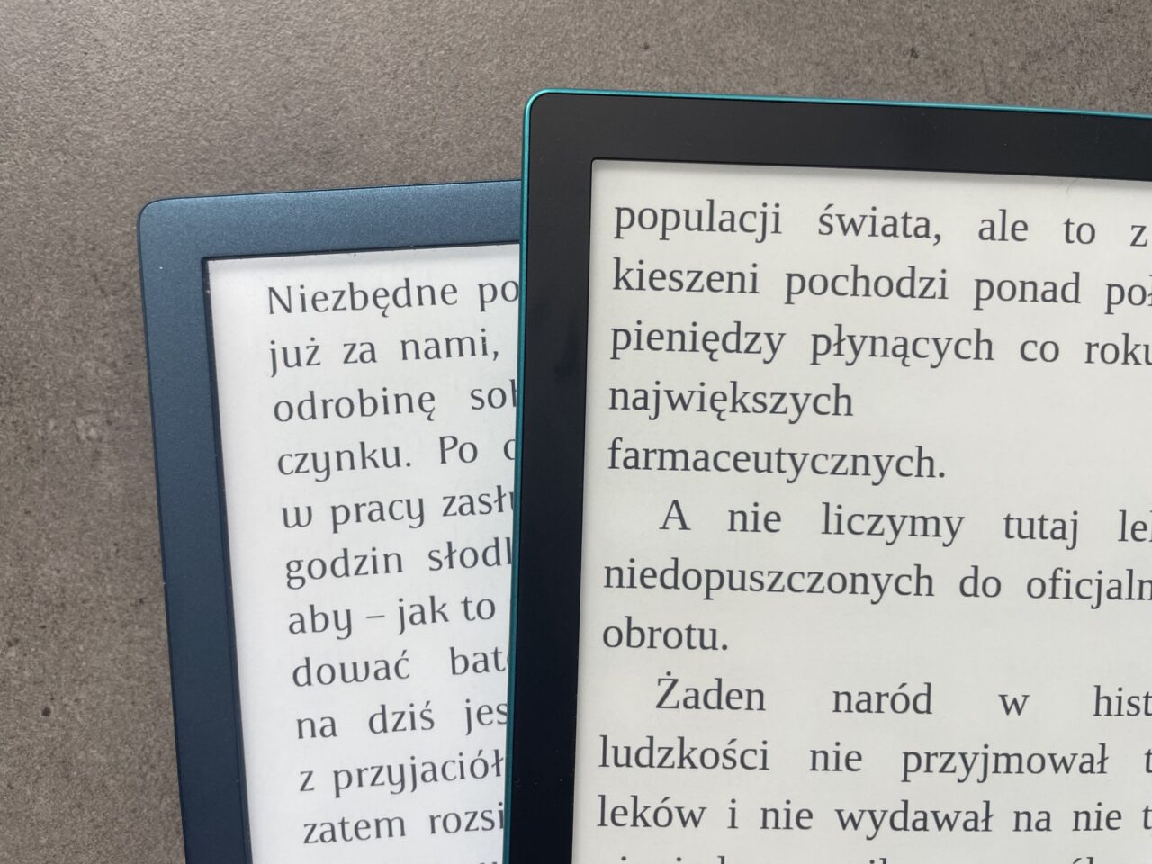 Dwa czytniki e-booków leżące obok siebie, jeden w niebieskiej obudowie widoczny częściowo po lewej stronie, a drugi w czarnej obudowie po prawej, oba z włączonym tekstem w języku polskim.