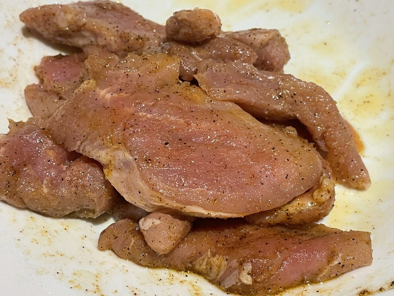 Pieczone plastry mięsa z przyprawami na talerzu.