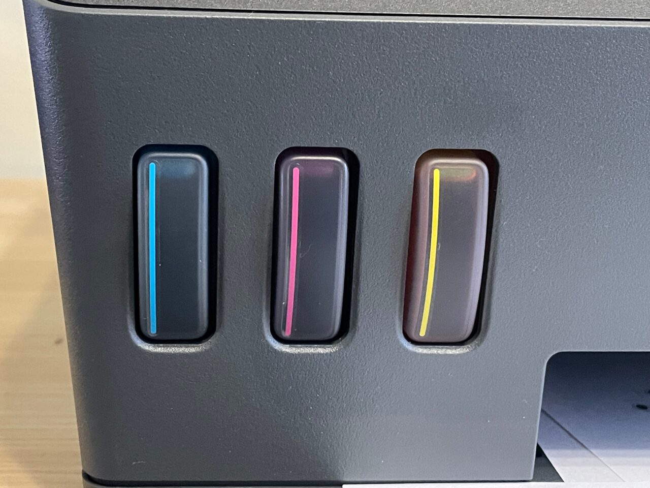 Część przednia komputera z trzema widocznymi poziomymi szczelinami na porty, z których każda ma kolorowy pasek: niebieski, różowy i żółty, na czarnym tle obudowy.