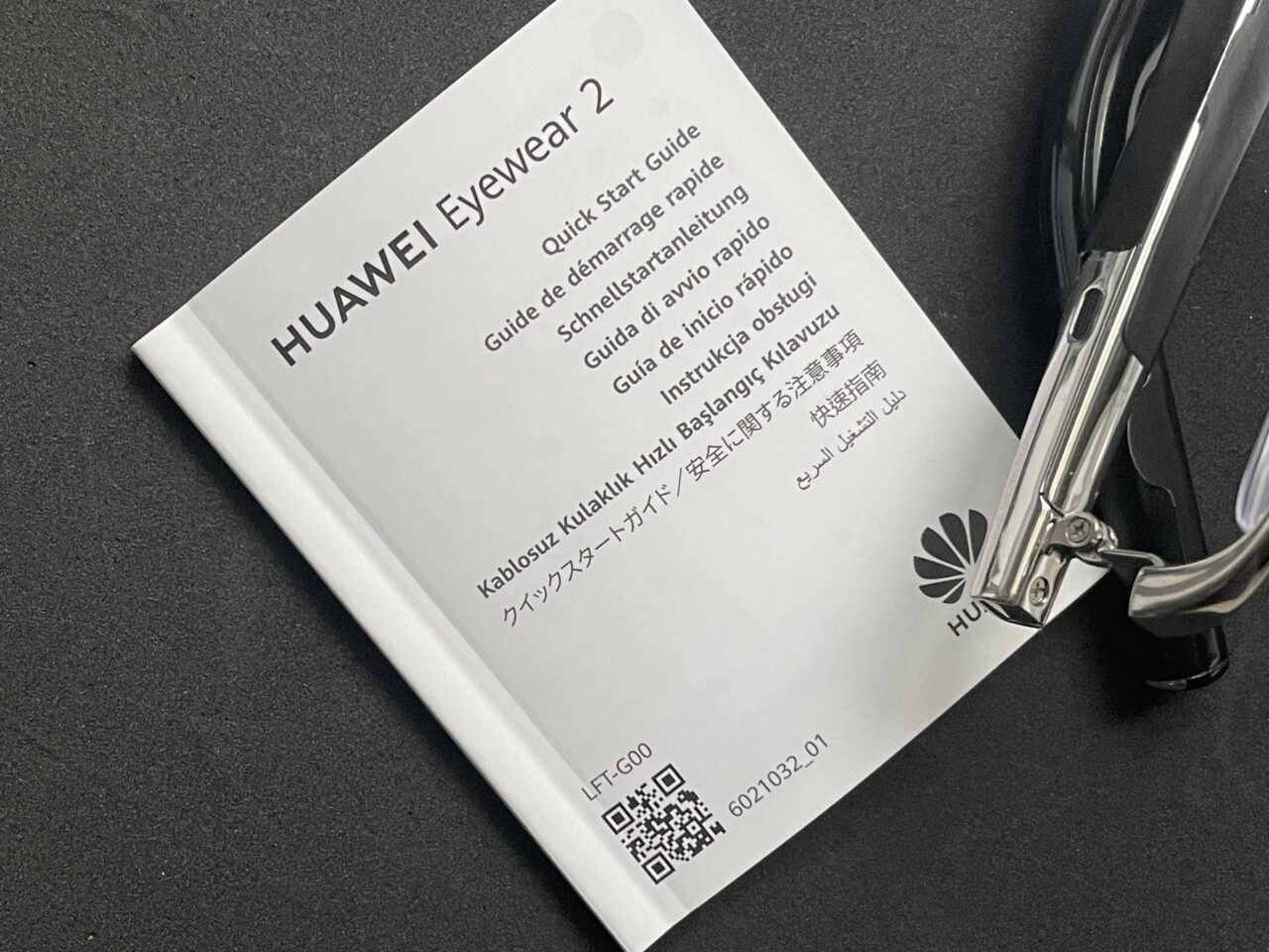 Instrukcja szybkiego startu dla produktu HUAWEI Eyewear 2 z kodem QR i przewodnikiem w różnych językach obok czarnej okularów.