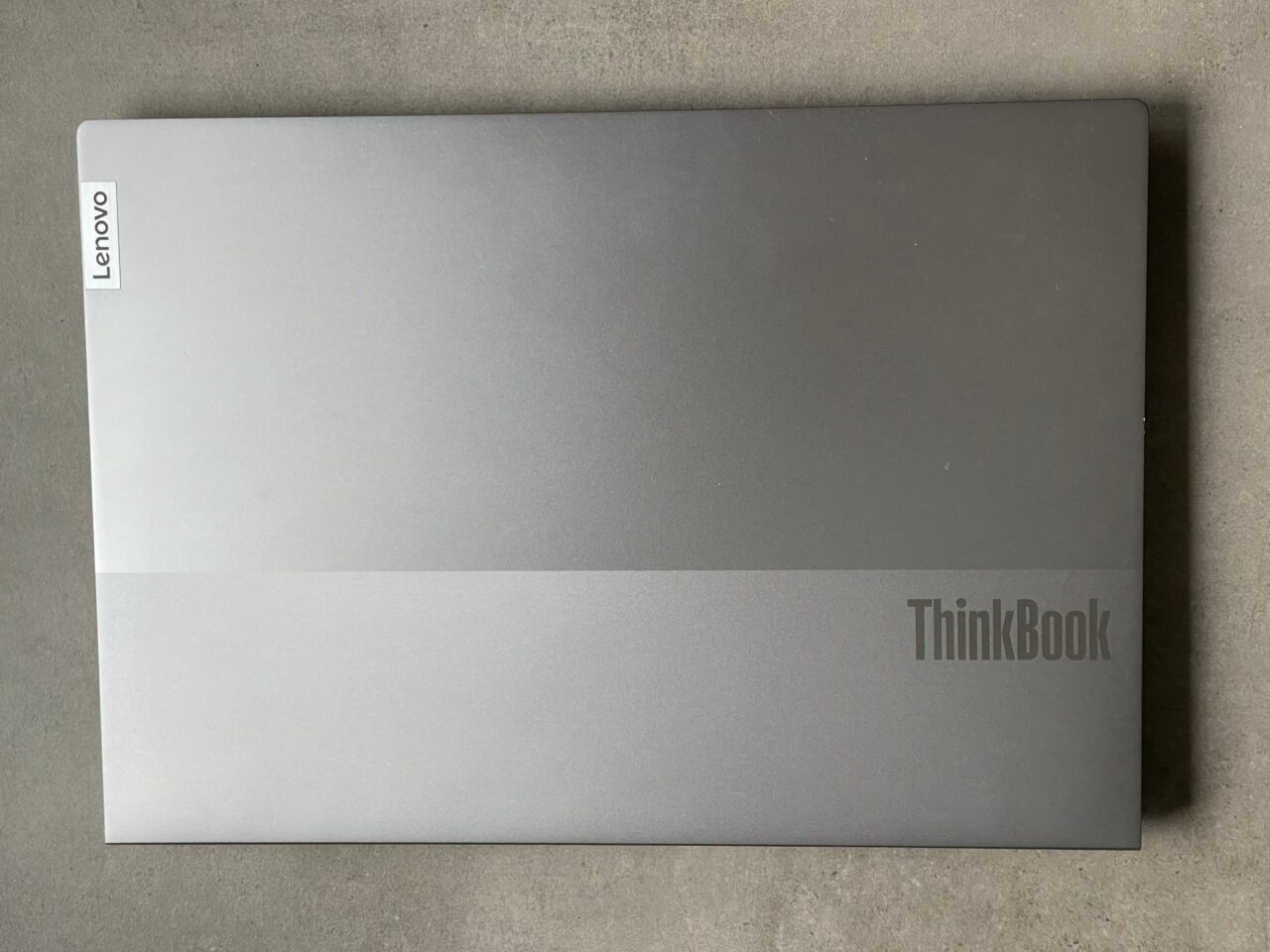 Zamknięty laptop Lenovo ThinkBook leżący na szarym tle.