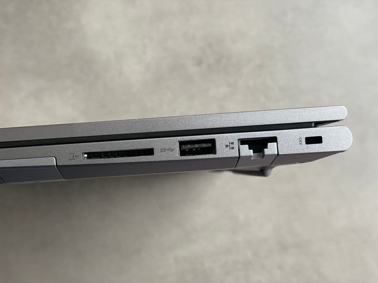 Bok laptopa z widocznymi portami: czytnik kart SD, USB, HDMI oraz Ethernet.