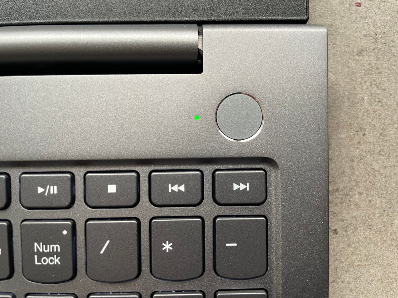 Część laptopa z widocznym przyciskiem zasilania, klawiszami multimediów i klawiszem Num Lock na klawiaturze.