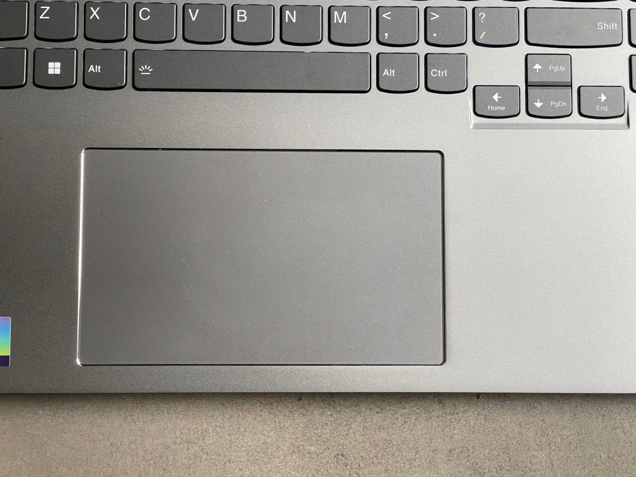 Część klawiatury laptopa i duży touchpad na jednolitym tle.