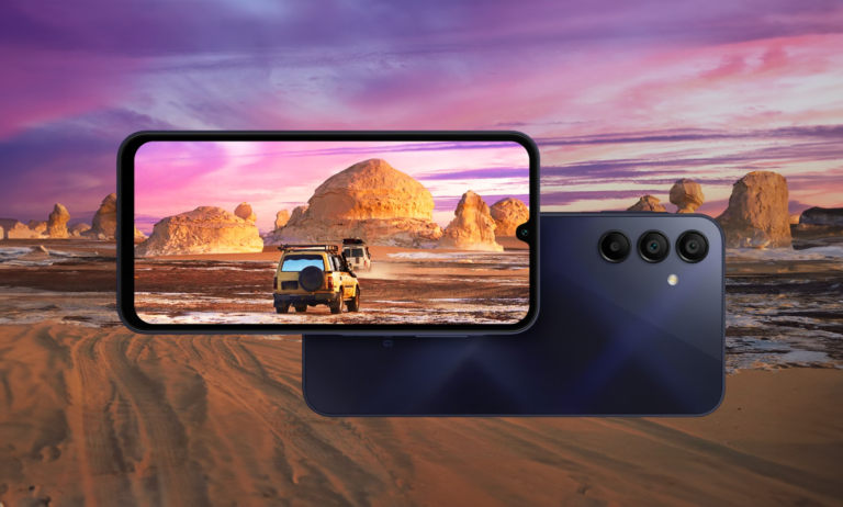 Smartfon z ekranem pokazującym zdjęcie jeepa w pustynnym krajobrazie z barwnym niebem o zmierzchu, oparty o drugi, wyłączony smartfon z potrójnym aparatem.
