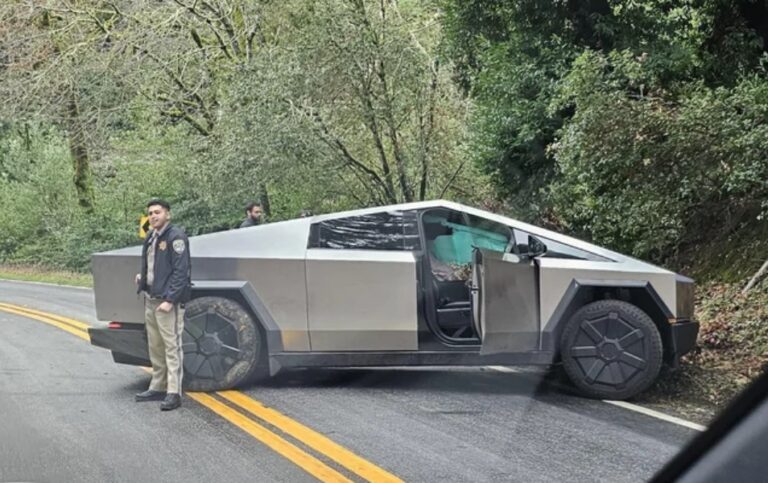 Tesla Cybertruck z otwartymi drzwiami stojąca w poprzek drogi po wypadku, dookoła ludzie