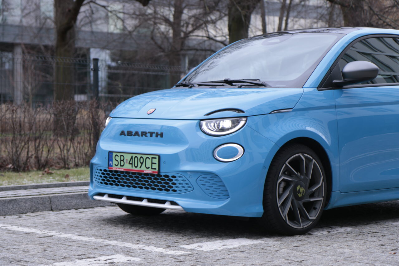 Niebieski samochód sportowy marki Abarth zaparkowany na bruku.