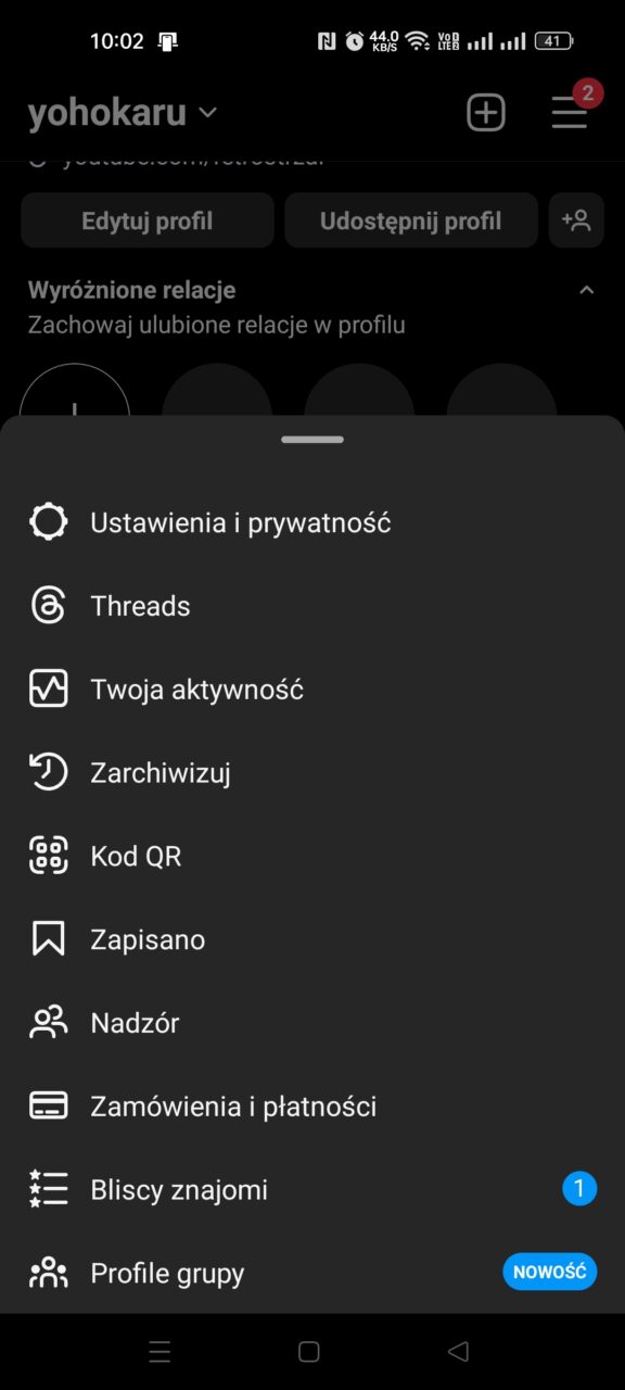 Zrzut ekranu menu profilu użytkownika w aplikacji mobilnej z czarnym tłem, zawiera opcje takie jak edycja profilu, ustawienia prywatności, archiwizowanie, kod QR i inne elementy nawigacji.