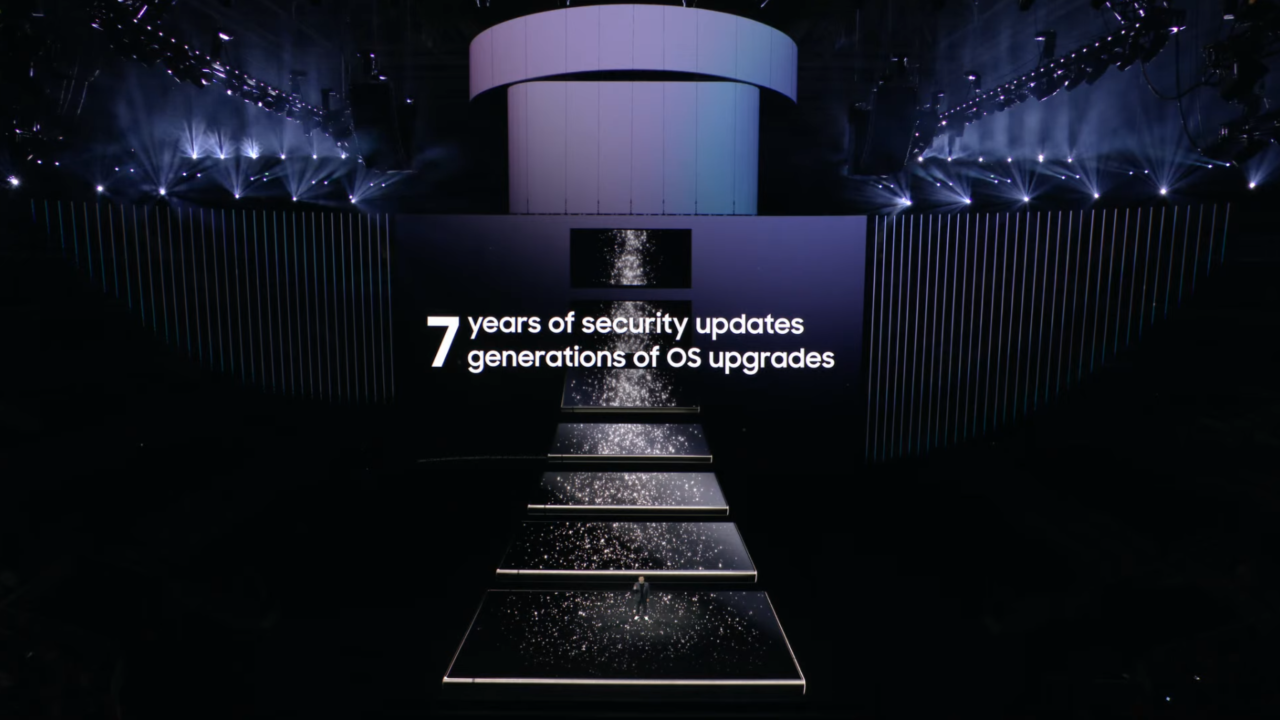 Scena prezentacji z tekstem "7 years of security updates 7 generations of OS upgrades" podświetlona reflektorami z ciemnym tłem.