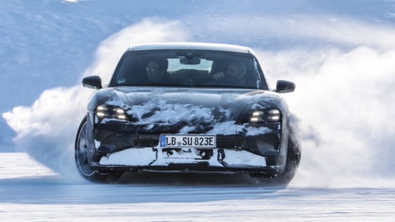Porsche Taycan. Czarny samochód jedzie z dużą prędkością po zasypanej śniegiem drodze, wokół unosi się chmura śniegu.