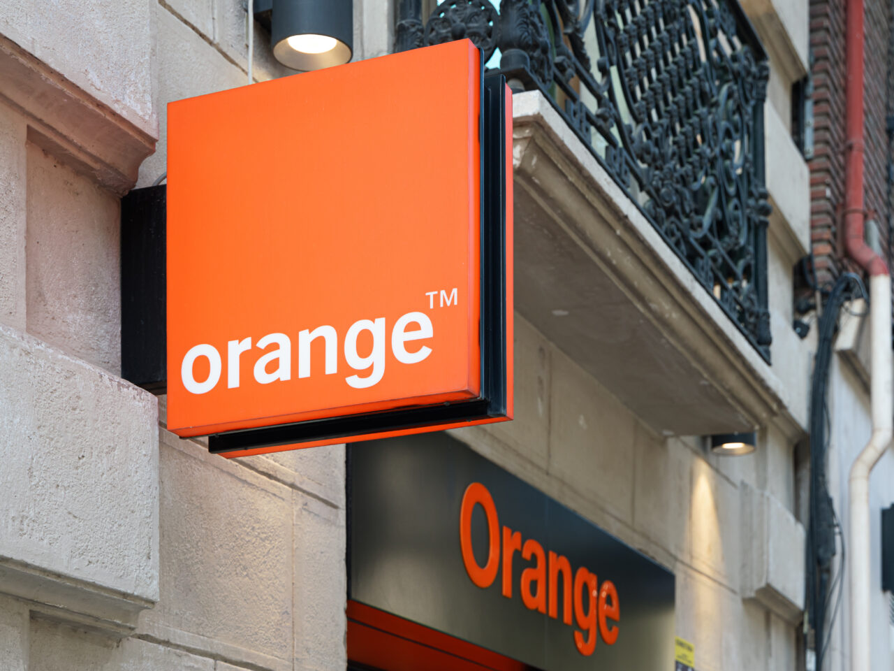 Tablica reklamowa operatora Orange™ zamontowana na zewnętrznej ścianie budynku.