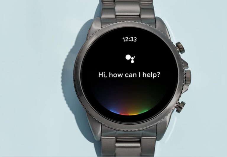 Inteligentny zegarek Fossil Gen 6 z metalowym paskiem wyświetlający wiadomość "Hi, how can I help?" oraz multikolorową paletę na tarczy.
