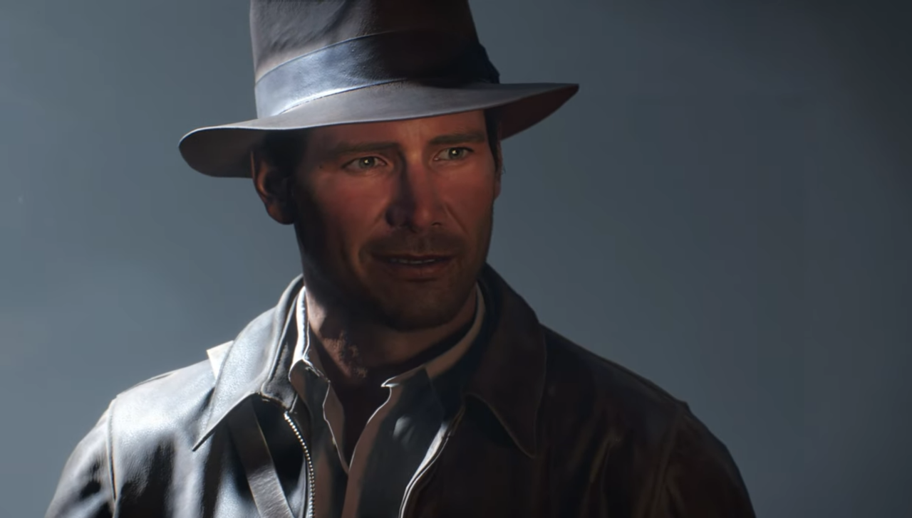 Kadr z gry Indiana Jones i Wielki Krąg. Mężczyzna w stylowym kapeluszu i skórzanej kurtce z zamyślonym spojrzeniem na ciemnym tle.