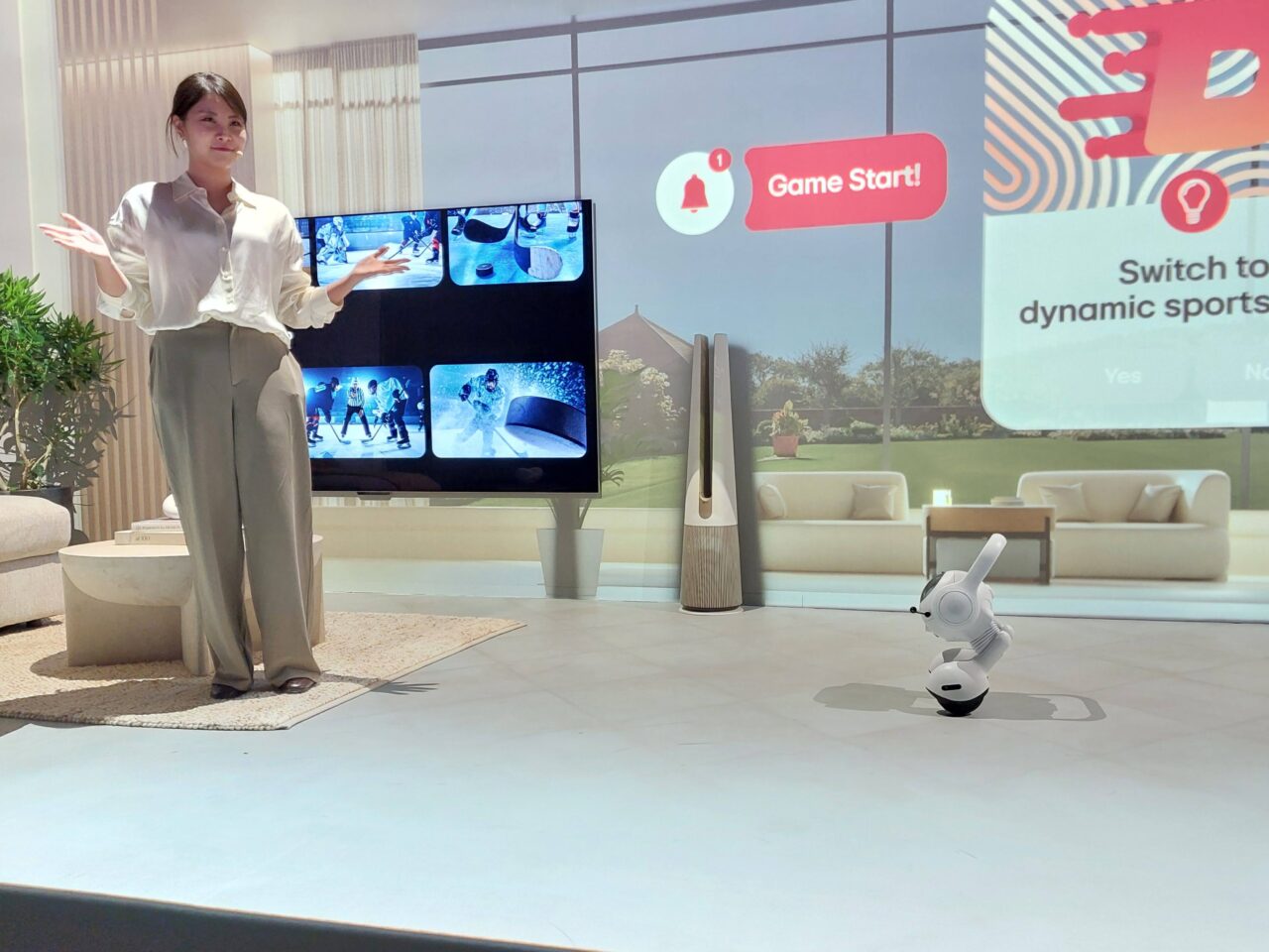 Kobieta prezentuje wnętrze z dużym telewizorem wyświetlającym obrazy sportowe, obok widoczny jest robot LG AI Agent, a w tle wyświetlana jest animowana grafika z opcją "Game Start".