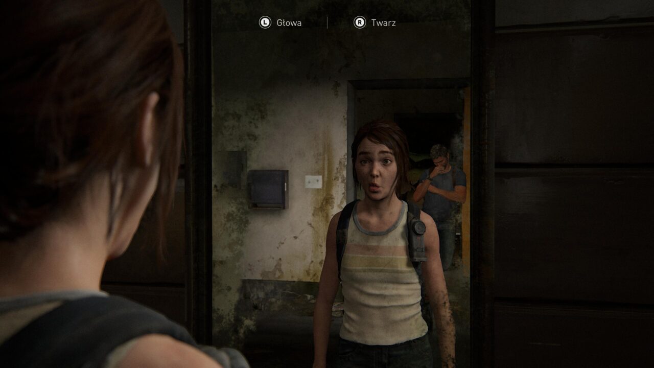 Scena z gry wideo The Last of Us Part II Remastered przedstawiająca młodą kobietę patrzącą w lustro z zaskoczonym wyrazem twarzy, w tle postać mężczyzny z zasłoniętą twarzą ręką. Na ekranie widoczne są opcje wyboru: "(L) Głowa" i "(R) Twarz".