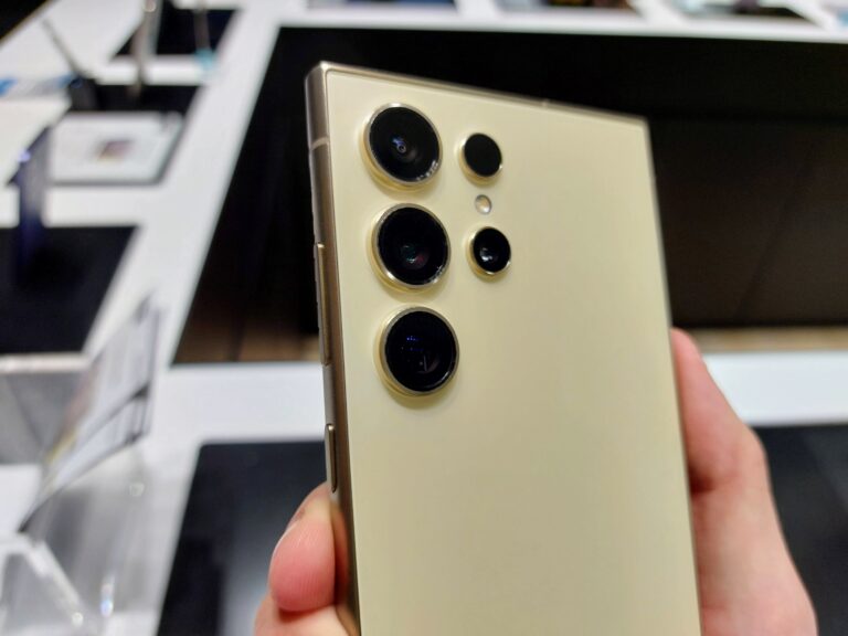 Złoty smartfon trzymany w ręce z tyłu, widać układ czterech obiektywów aparatu i dodatkowych sensorów.