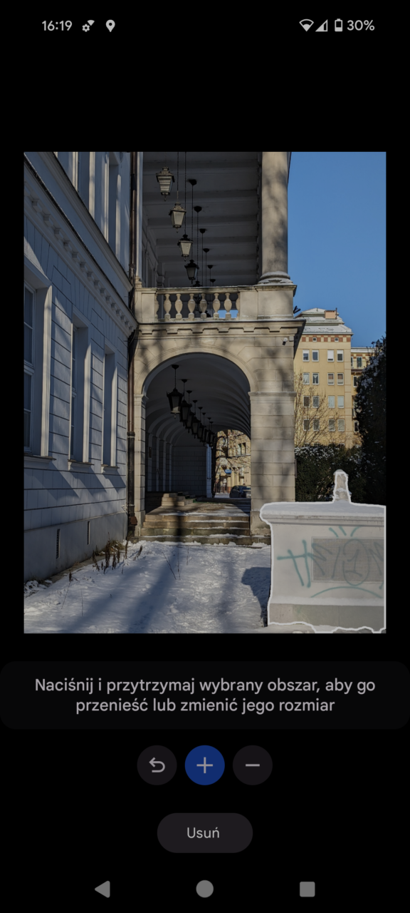 Klasyczna architektura kolumnowego ganku z latarniami, śnieg na ziemi i bezbarwny graffiti na murze na pierwszym planie.