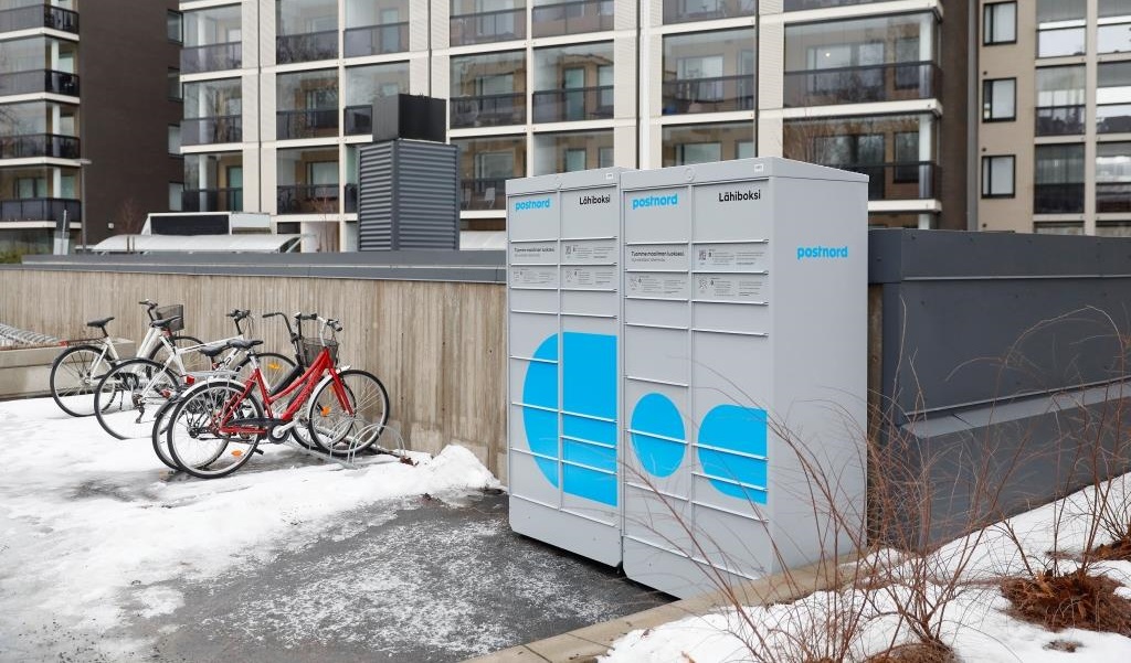 automaty paczkowe stojące przed budynkami obok stojaków na rowery w zimowym krajobrazie
