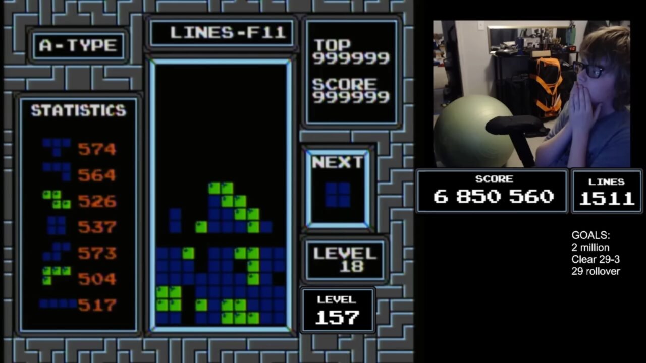 Osoba siedząca przy komputerze, koncentruje się na grze Tetris, wyświetlanej na ekranie, z wynikiem 6 850 560 punktów i poziomem 157.