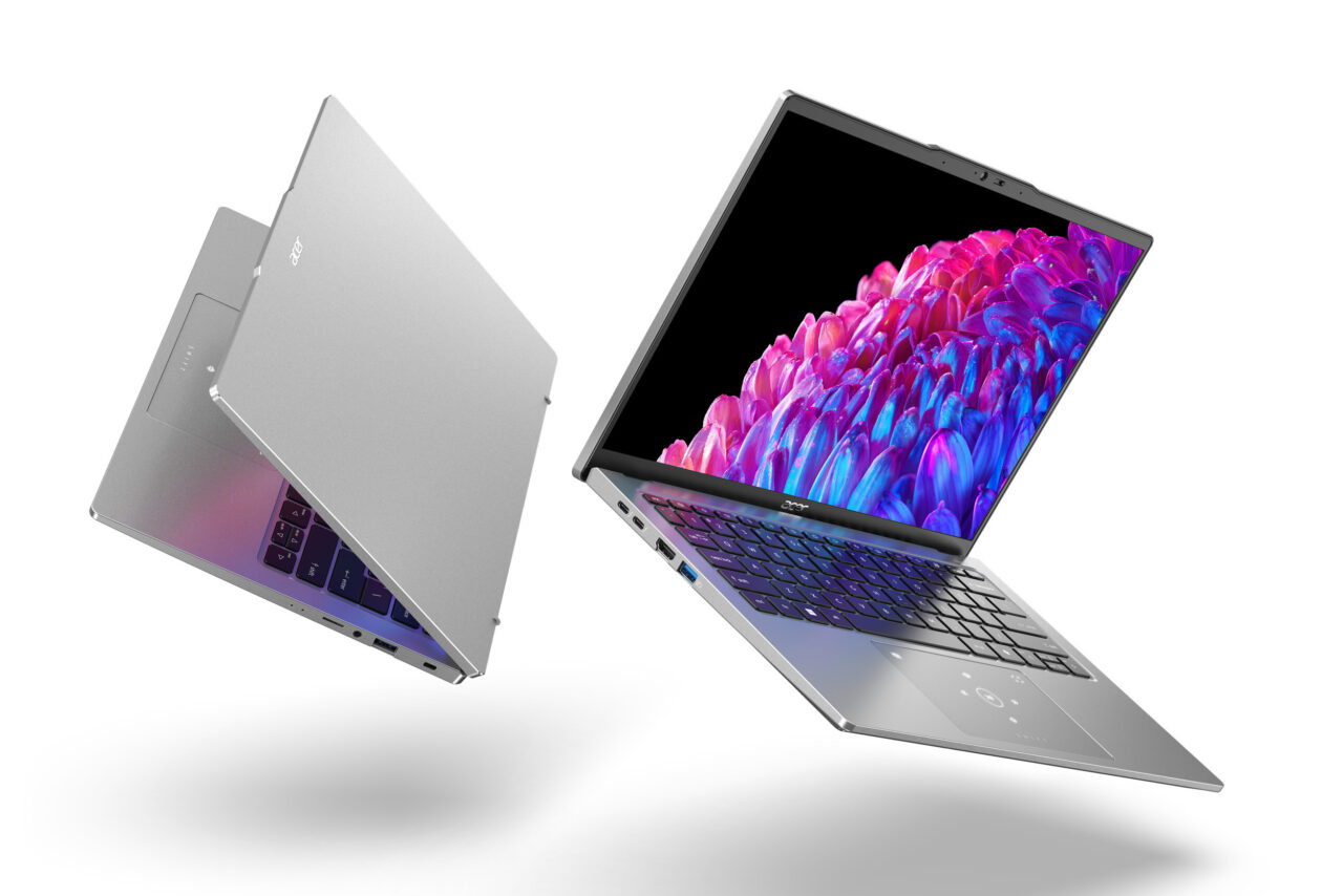 Dwa srebrne laptopy z otwartymi klapami, jeden leżący tyłem, a drugi ustawiony pod kątem, z widocznym kolorowym obrazem na ekranie.