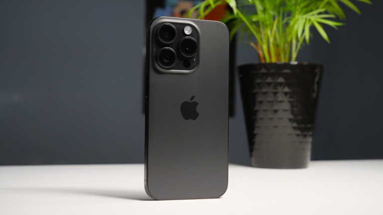 Czarny iPhone 15 Pro z potrójnym aparatem na tle doniczki z rośliną.
