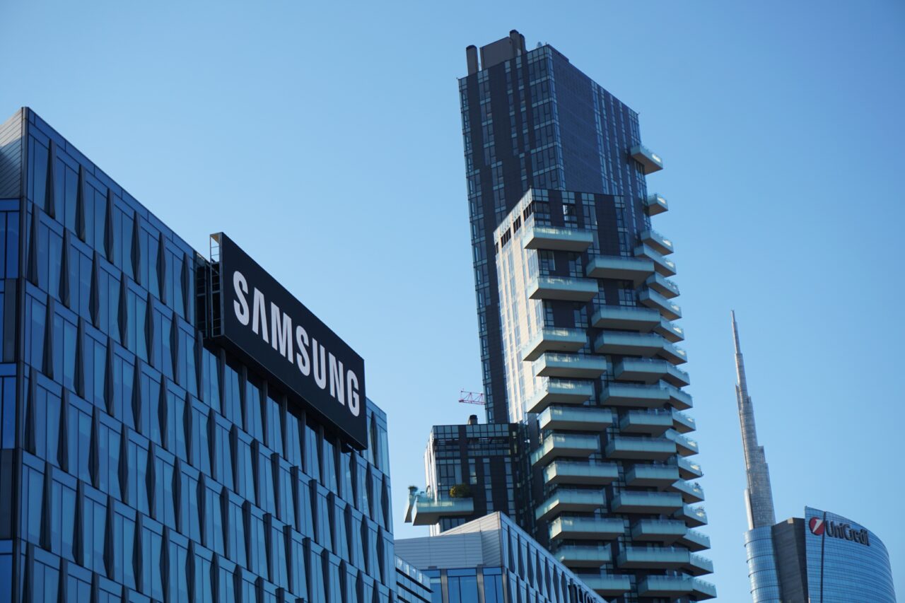 Biurowce z logo firmy Samsung, wieżowiec mieszkalny oraz częściowe widoczne siedziby innych firm na tle niebieskiego nieba.