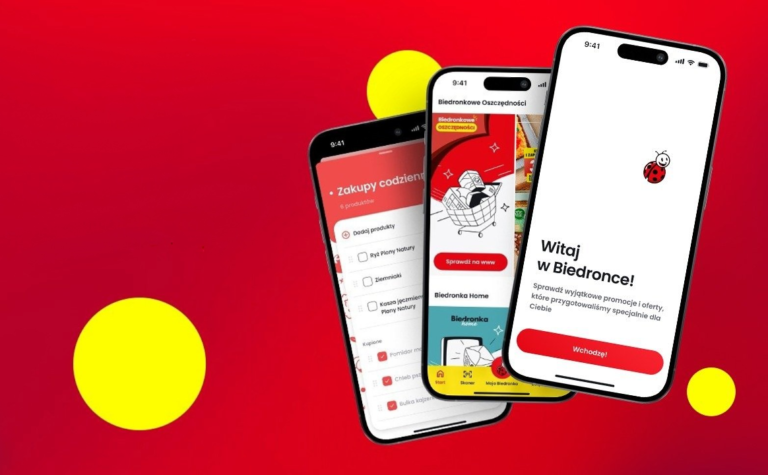Dwa smartfony z ekranami pokazującymi interfejs aplikacji sklepu Biedronka na czerwonym tle z żółtymi okrągłymi elementami graficznymi.