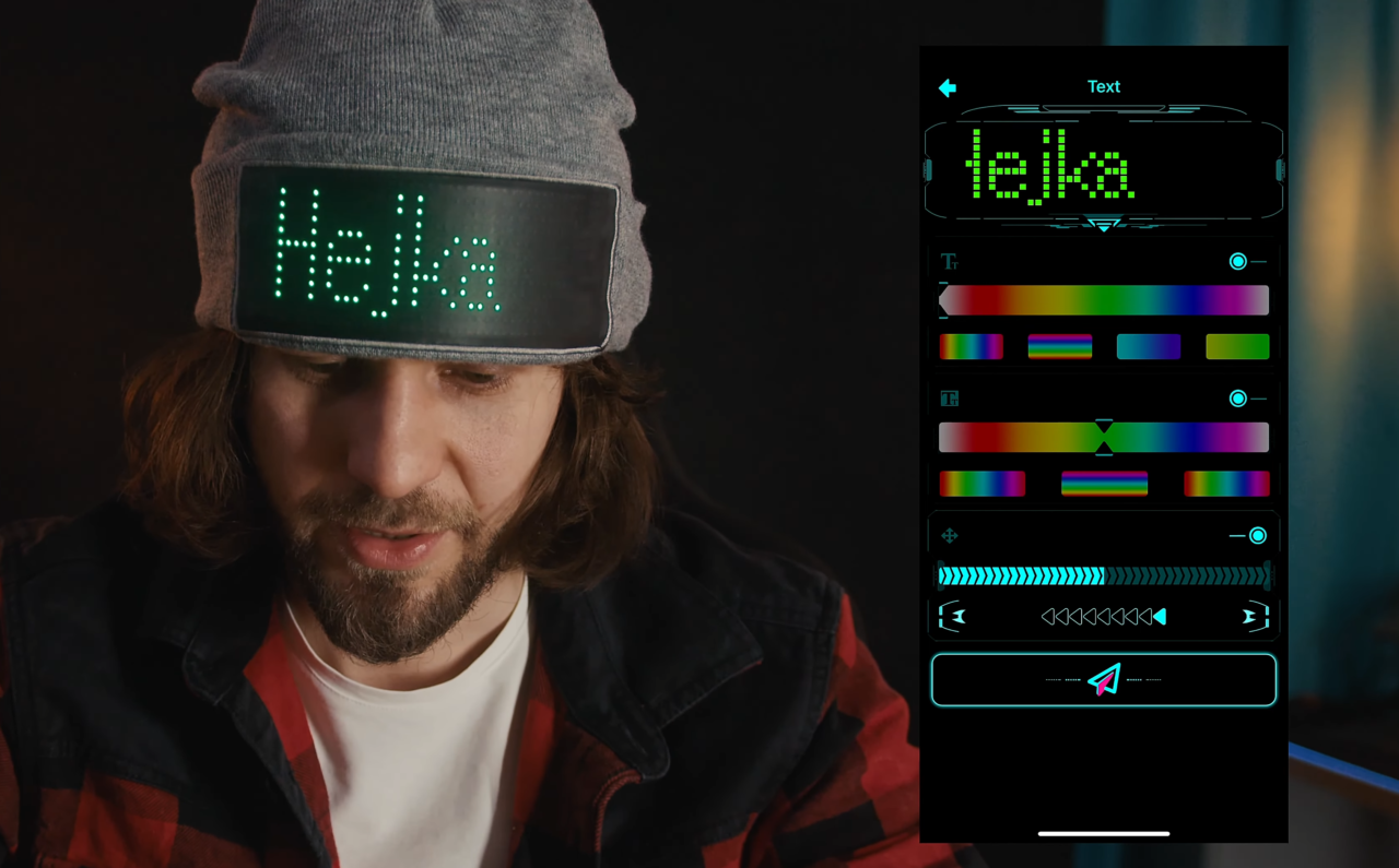 Mężczyzna w szarej czapce wyświetlającej wiadomość "Hejka" za pomocą zielonych diod LED, obok interfejs użytkownika umożliwiający edycję wyświetlanej wiadomości i jej kolorów.