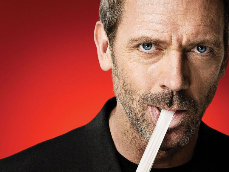 Hugh Laurie jako Dr House. Mężczyzna w średnim wieku z zarostem, patrzący intensywnie w kamerę, trzyma w ustach termometr. Tło jest czerwone.