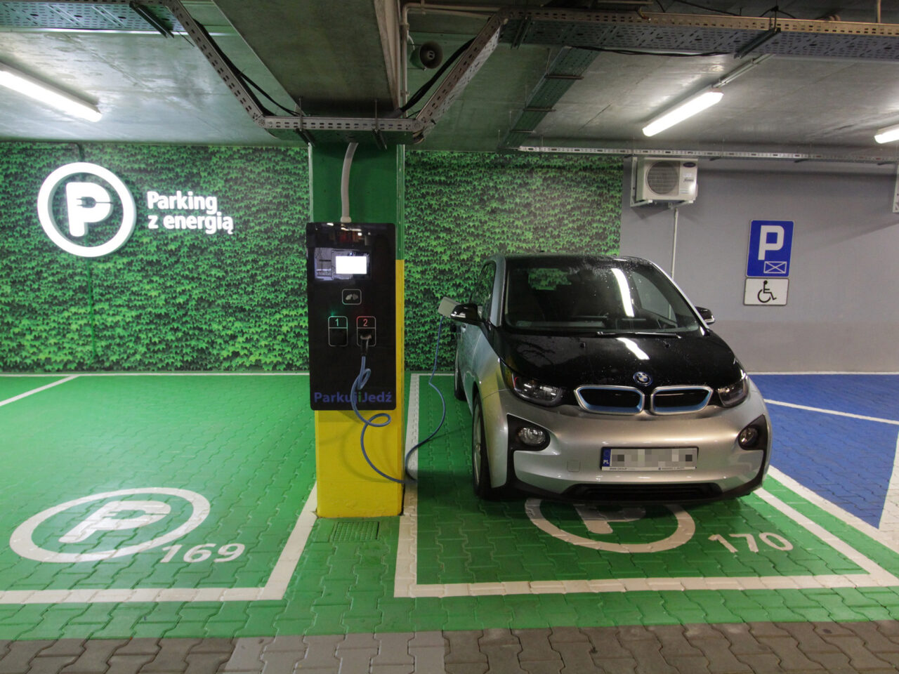 Elektryczny samochód BMW i3 podłączony do stacji ładowania. Prezentacja miejsca, na którym mogą parkować samochody elektryczne na warszawskim parkingu „Parkuj i Jedź” ZTM