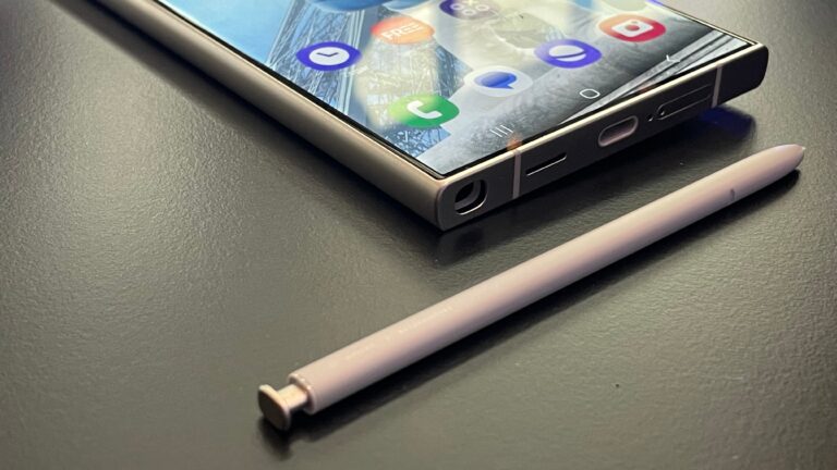 Smartfon Samsung Galaxy S24 Ultra leżący na ciemnym blacie obok różowego cyfrowego rysika.
