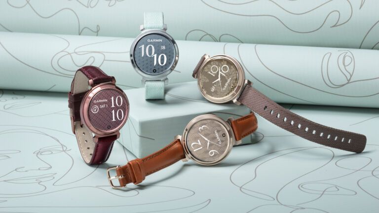 Cztery zegarki Garmin o różnych stylach i kolorach pasków, wyeksponowane na tle zwojów papieru z rysunkami.