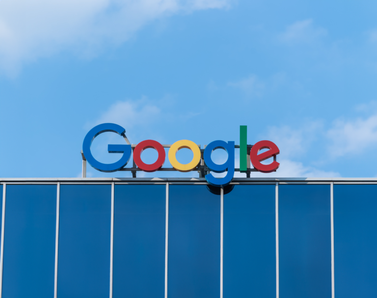 Logo Google umieszczone na szczycie budynku, z niebieskim niebem w tle.