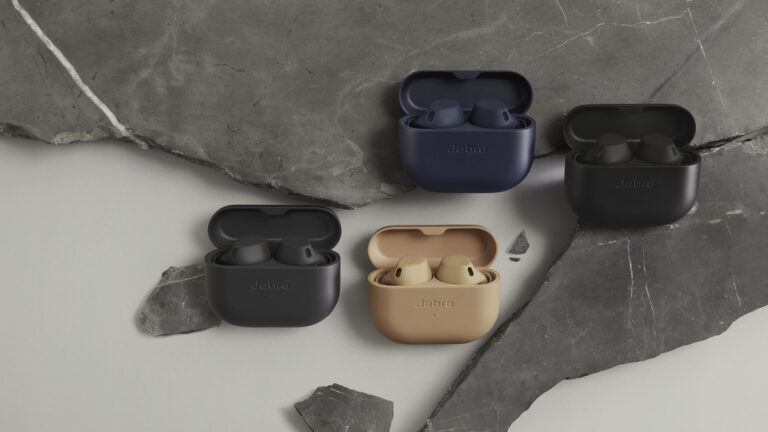 Trzy pary bezprzewodowych słuchawek dousznych marki Jabra w otwartych etui, ułożone na płaskim kamiennym podłożu o odcieniach szarości.