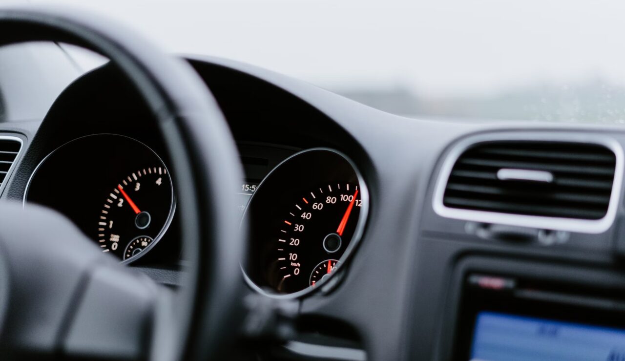 zmiany w podatku od samochodów spalinowych Wnętrze samochodu z widokiem na kierownicę i deski rozdzielczej z zegarami prędkościomierza i obrotomierza.