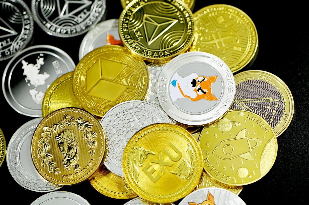 Zbiór różnych kolorowych monet reprezentujących kryptowaluty, takich jak Bitcoin i Ethereum, rozproszonych na czarnym tle.