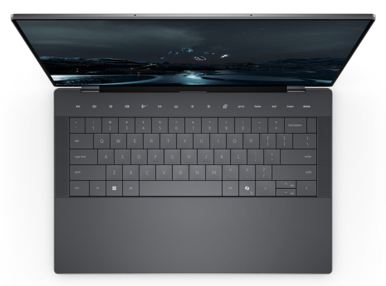 Laptop z otwartą klapą i widoczną klawiaturą oraz ekranem wyświetlającym krajobraz nocny z aurorą borealis.