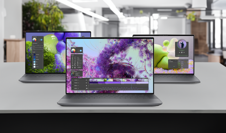 Trzy laptopy na biurku z włączonymi ekranami pokazującymi różne graficzne i wideo interfejsy użytkownika.