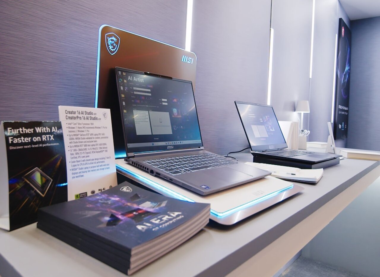 Biurko z trzema laptopami marki MSI, materiałami promocyjnymi i broszurami w nowoczesnym biurze.