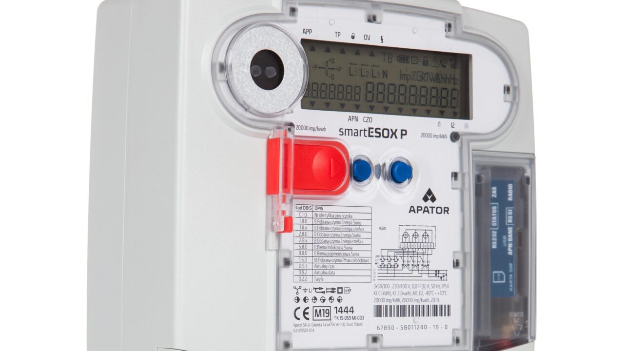 Licznik elektryczny APATOR typu smartESOX P z wyświetlaczem LCD, czerwonym i niebieskim przyciskiem oraz różnymi etykietami i oznaczeniami technicznymi.